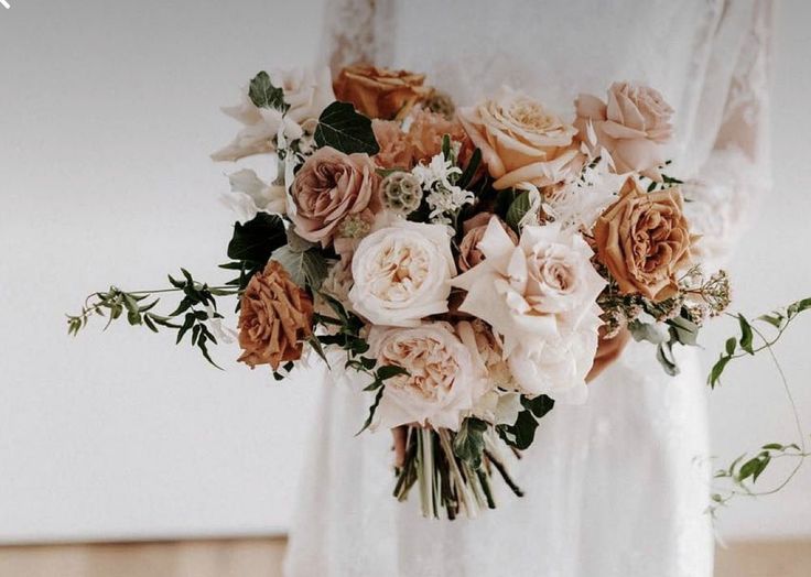 a bridal holding a bouquet of peach and white flowers