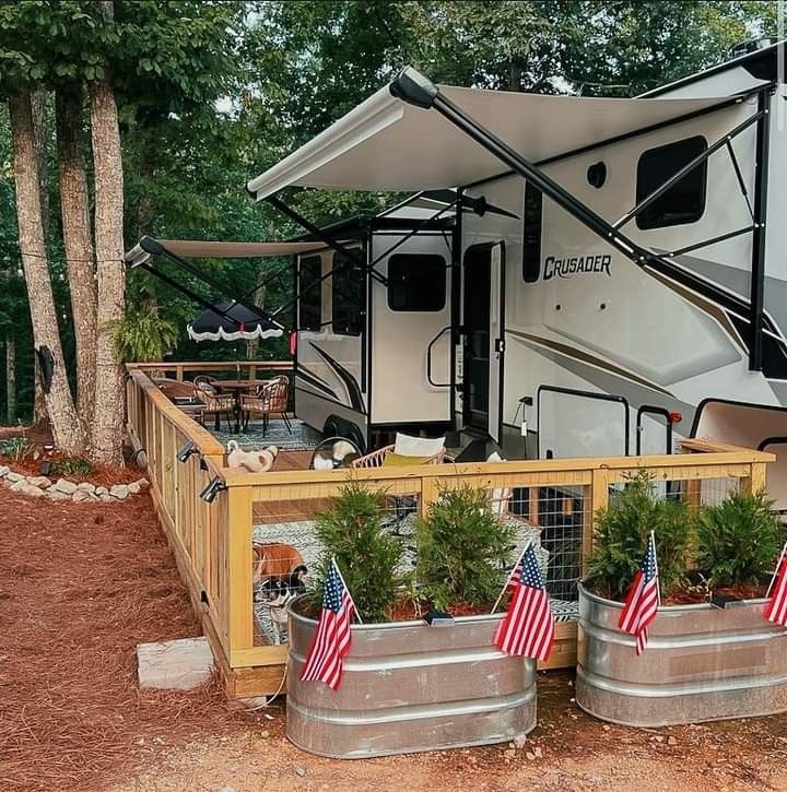 an rv parked next to some trees and flags