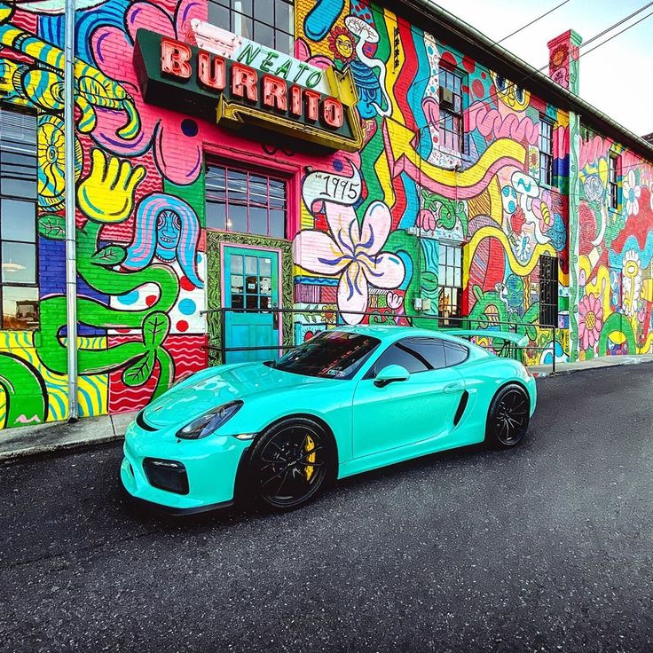 a blue sports car parked in front of a colorful building