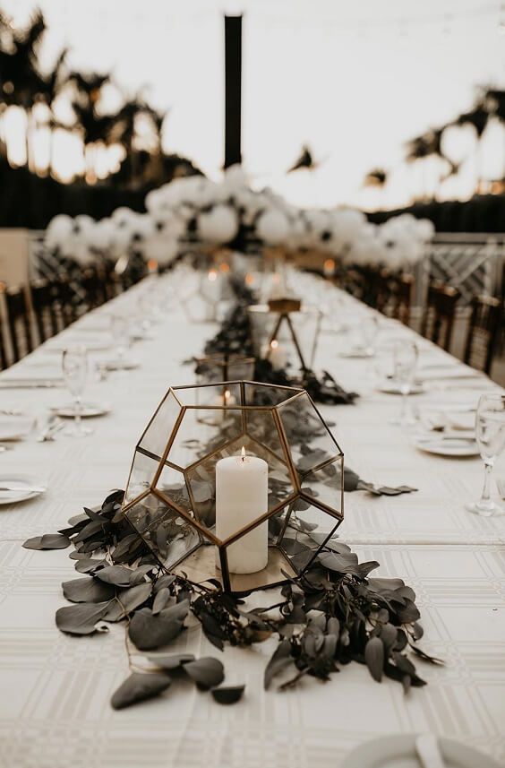 a long table is set with candles and place settings for an outdoor wedding reception at dusk