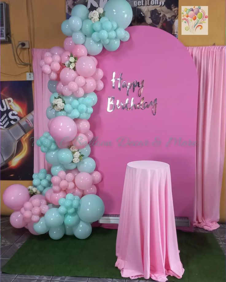 balloon arch with happy birthday sign and pink table cloth on green carpeted flooring