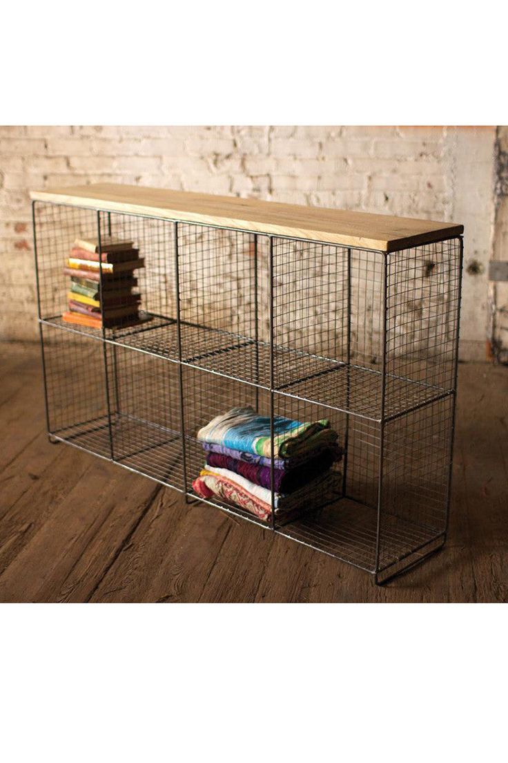 a metal shelf with books and magazines in it on a wooden floor next to a brick wall