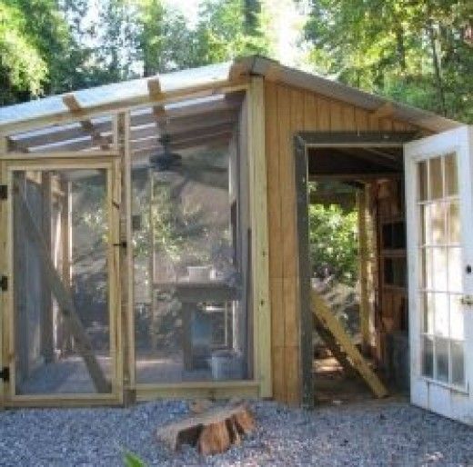 a chicken coop built into the side of a wooded area with an open door and windows