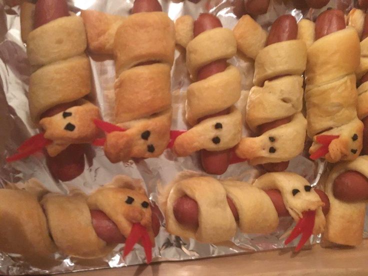 hotdogs wrapped in bread are arranged on tin foil and ready to be eaten