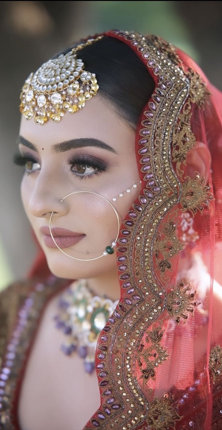 a woman wearing a red and gold bridal veil with an elaborate head piece on her head