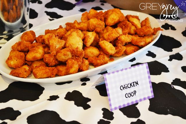 a white plate filled with fried chicken next to a glass of water on a black and white table cloth