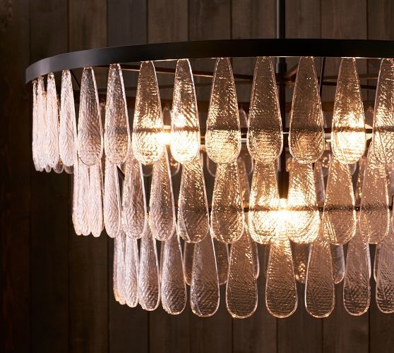 a chandelier made out of wine glasses hanging from a ceiling fixture with wood planks in the background