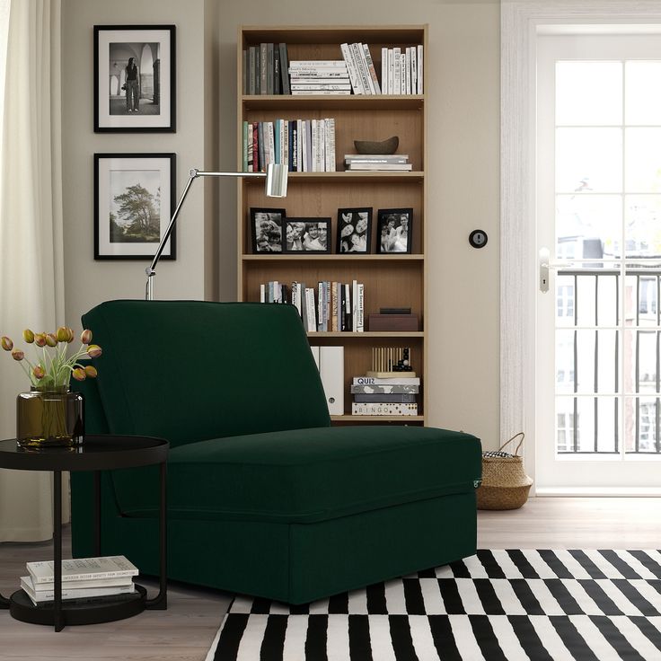 a living room with a gray chair and bookshelf in the corner, next to a black and white striped rug