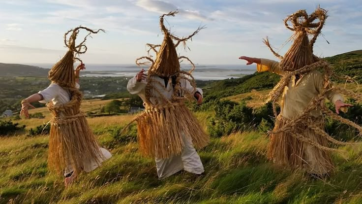 three scarecrows are walking in the grass with their heads turned to look like they're dancing