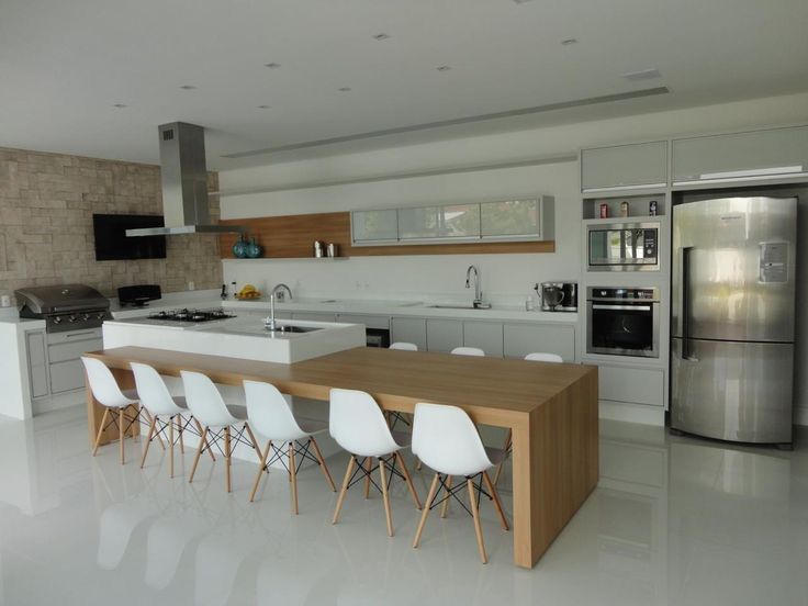 a modern kitchen with white chairs and an island table in front of the stove top