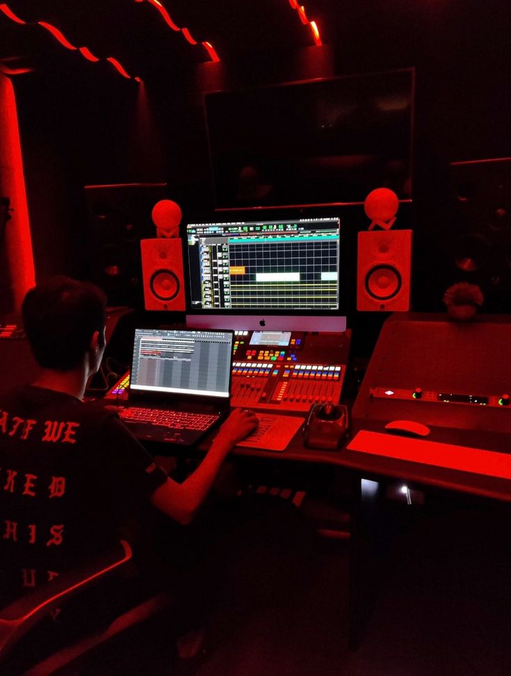 a person sitting at a desk with a laptop and sound equipment in front of him