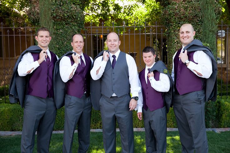 a group of men standing next to each other wearing purple vests and white shirts