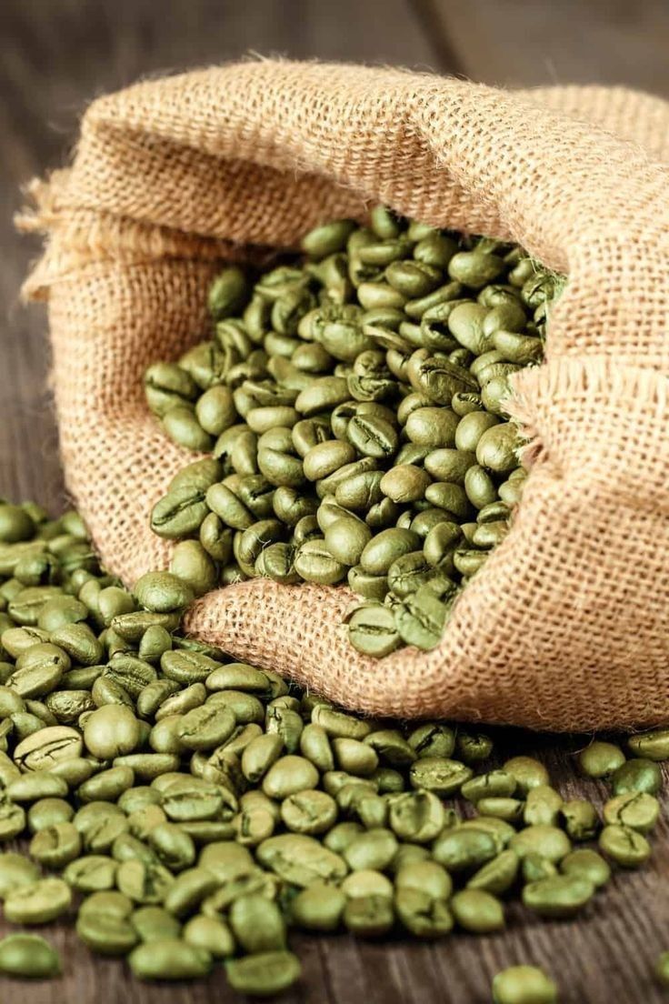 green coffee beans spilling out of a burlocked bag on a wooden table