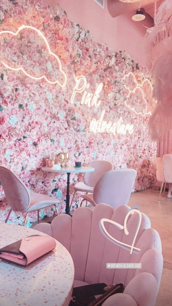 the interior of a restaurant with pink chairs and flowers painted on the wall behind it