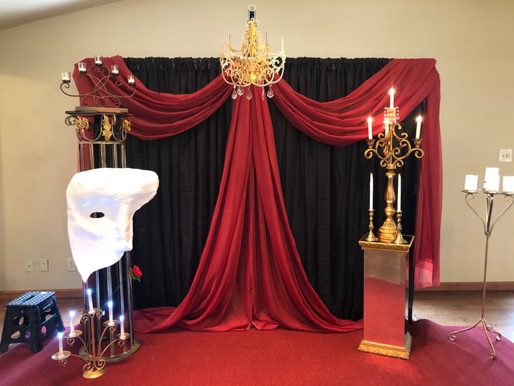 a stage set up with red curtains and candles