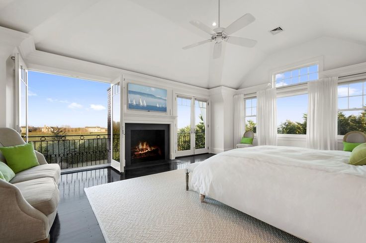 a large bedroom with a fireplace in the center and lots of windows on both sides