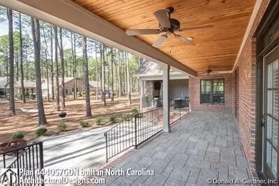 a covered porch with a ceiling fan and wood flooring in front of the house