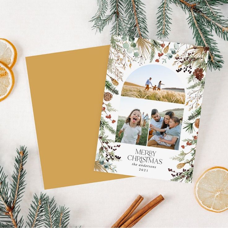 a christmas card with an orange slice and pine cones on the table next to it