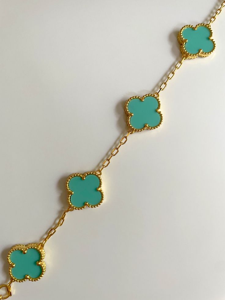 Adorn your wrist in elegance with our exquisite Clover Bracelet. Inspired by the iconic symbol of luck, this bracelet is crafted from the finest gold plating. Elevate any outfit with this sophisticated and exclusive piece, perfect for those with a taste for luxury. Elegant Turquoise Bracelet Jewelry, Elegant Green Metal Charm Bracelet, Elegant Turquoise Bracelet, Luxury Gold Plated Charm Bracelet, Elegant Turquoise Adjustable Charm Bracelet, Elegant Turquoise Jewelry, Tarnish Resistant, Elegant Blue Bangle Charm Bracelet, Elegant Green Jewelry With Bracelet Strap, Elegant Blue Metal Chain Bracelet