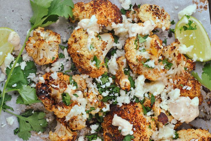 some cauliflower and other food on a plate with lime wedges next to it