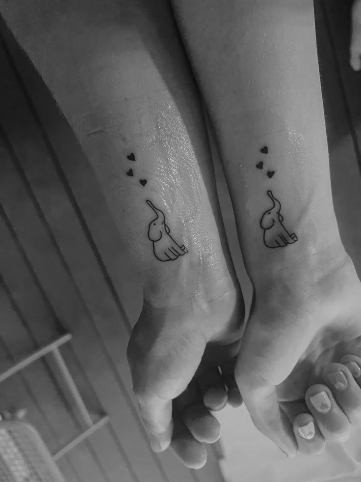 two people with matching tattoos on their feet, one is holding the other's hand