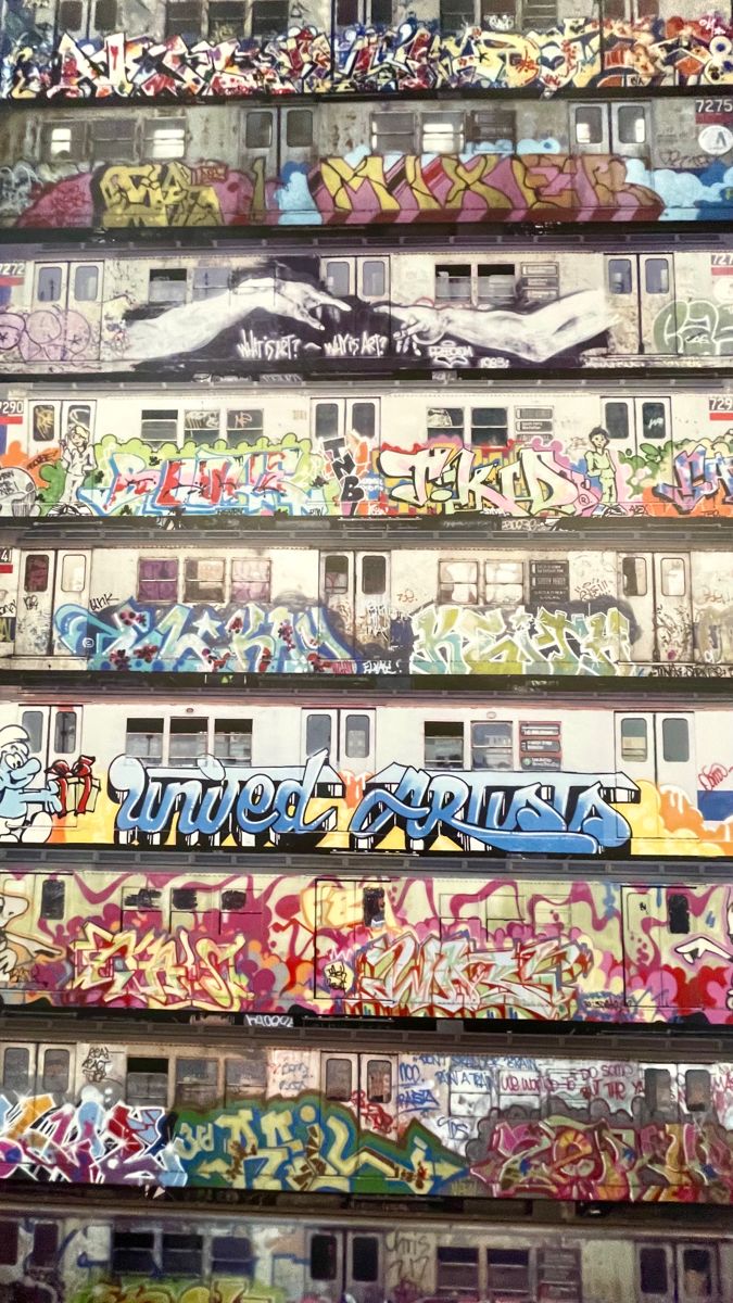 several train cars covered in graffiti sitting on top of each other's sides with windows