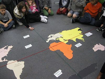 a group of children sitting on the floor around a world map