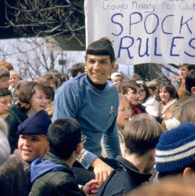 a young man standing in front of a crowd holding a sign that says spock rules