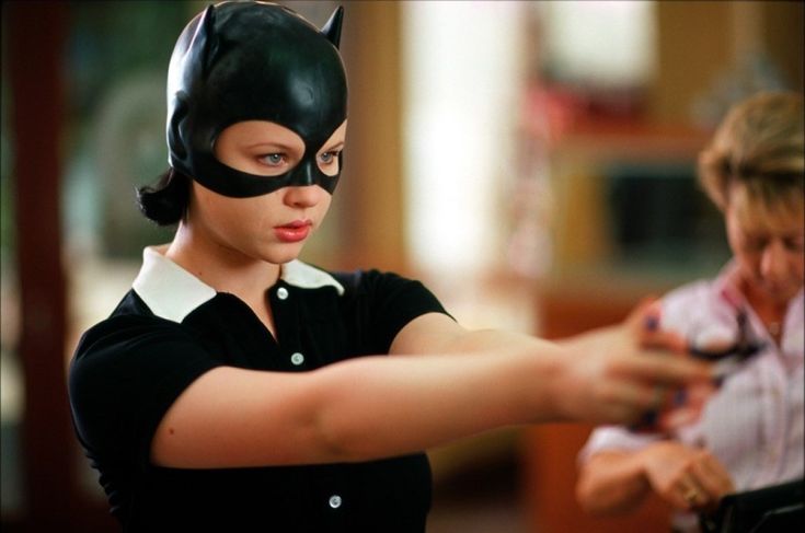 a woman wearing a cat mask and pointing at something