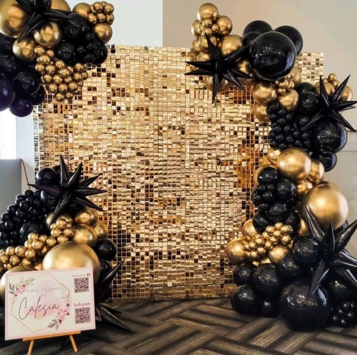 some black and gold balloons are in front of a large golden frame with starbursts on it