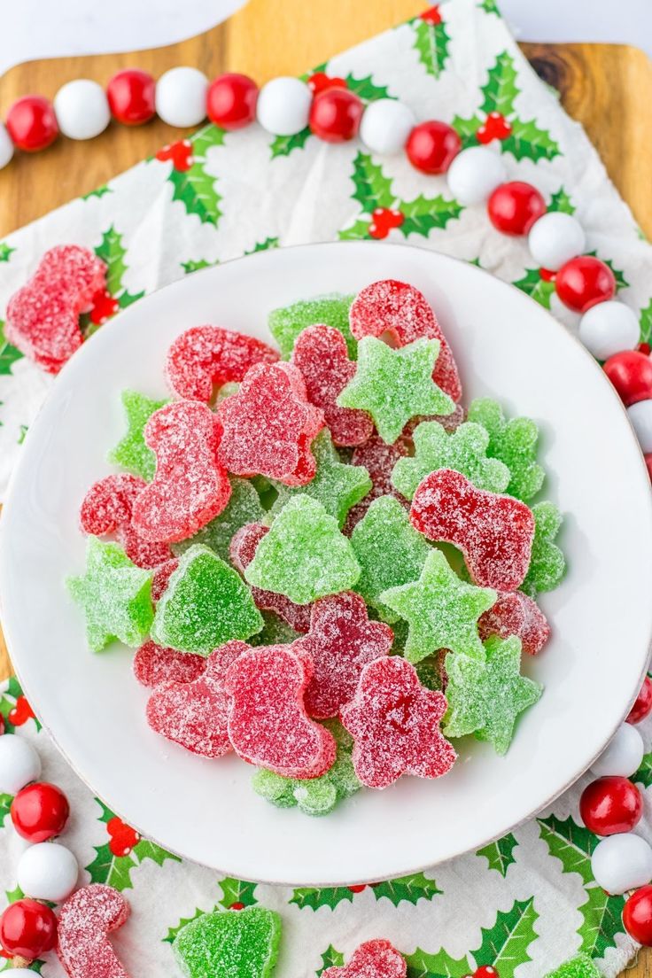 a white plate topped with gummy bears on top of a wooden table next to christmas decorations