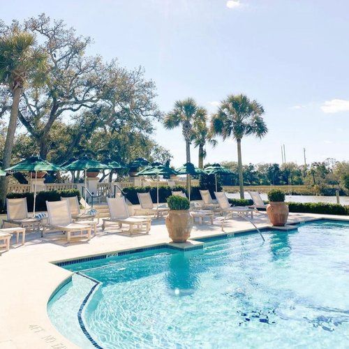 an outdoor swimming pool with lounge chairs and umbrellas