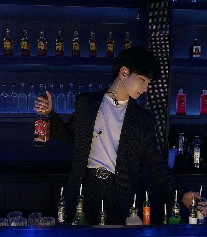 a man standing behind a bar filled with liquor bottles