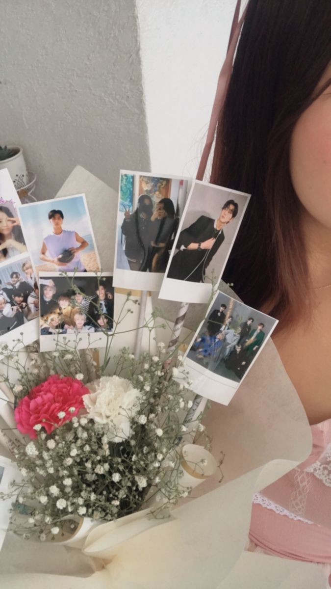 a woman holding flowers and photos in her hand