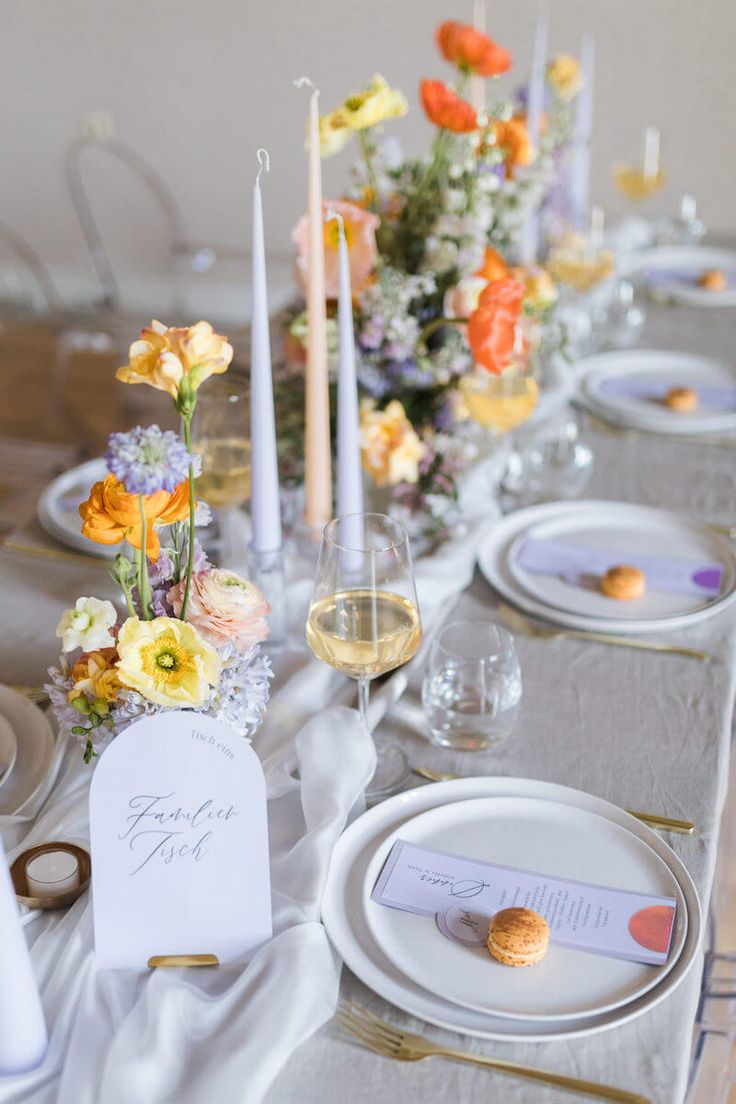 the table is set with place cards, wine glasses, and flowers in vases