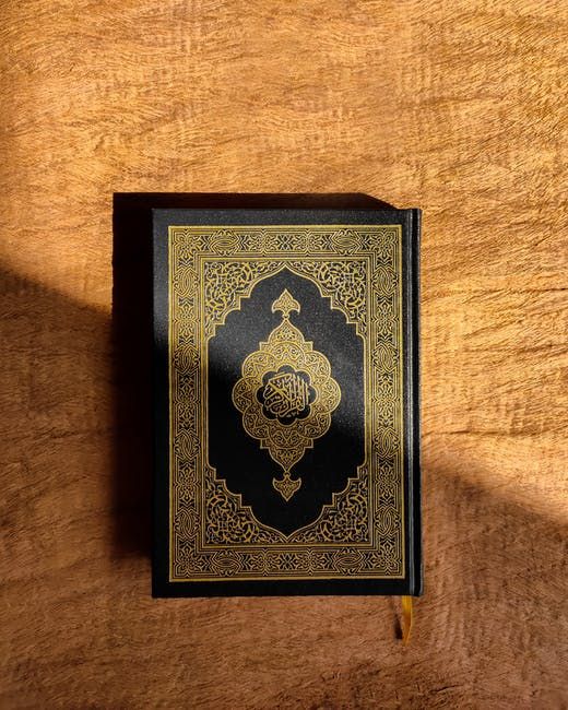 a black and gold book sitting on top of a wooden table next to a wall