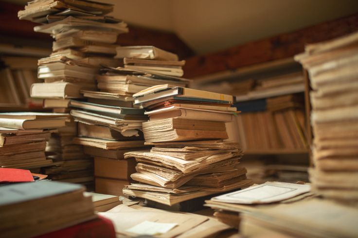 a stack of books sitting on top of a table next to a pile of papers