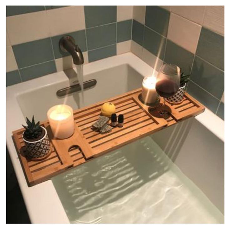 a bathtub tray with candles, soap and other items sitting on top of it