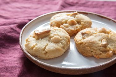 three cookies on a white plate sitting on a purple cloth