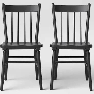 two black wooden chairs side by side on a white background, one is facing the other