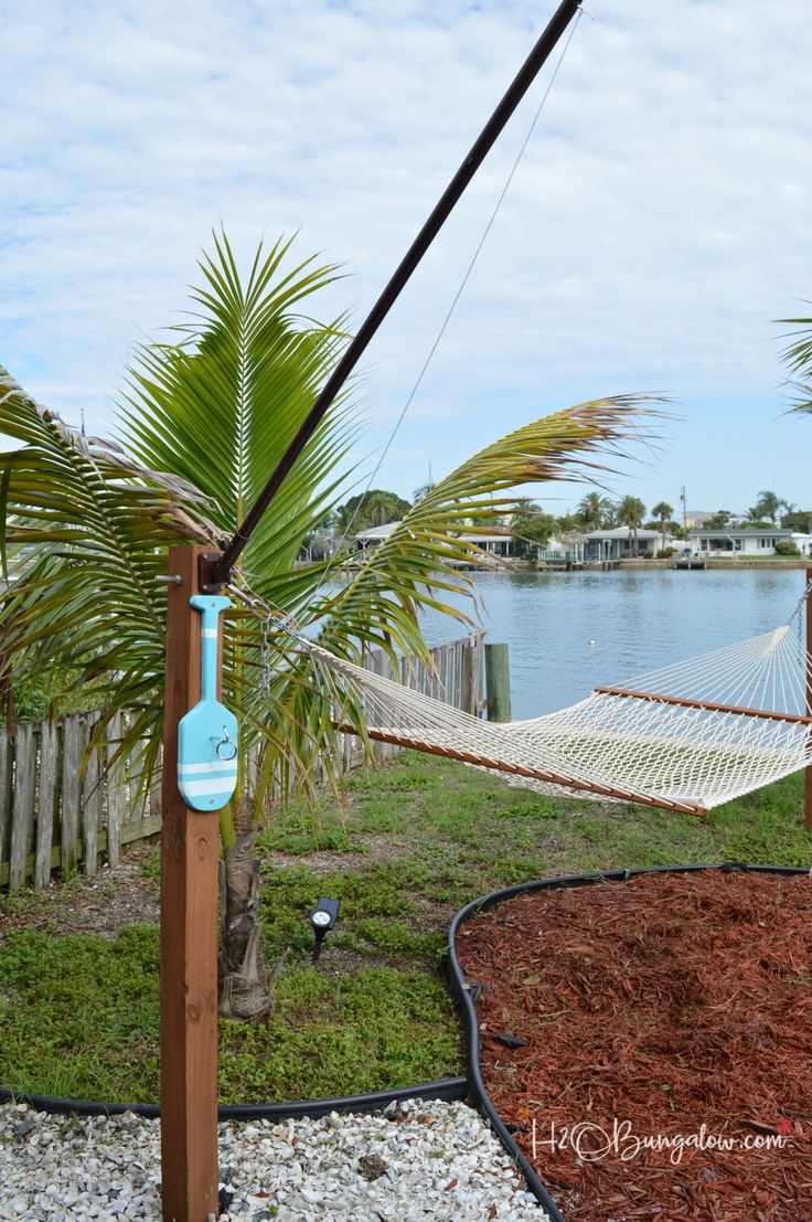 a hammock hanging from a wooden pole next to a body of water