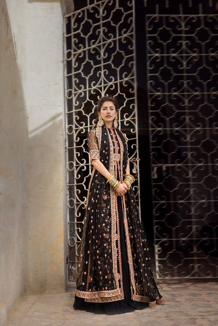 Chiffon Long Pishwas Lehenga Pakistani Party Dresses come in a black canvas tailored into a front slit open gown with elaborate floral embroidery all over and handworked borders and sleeves. It is paired with a flowy sharara and a sheer dupatta brushed with delicate coral motifs. Pishwas: An enchanting pishwas in black color tailored on a black canvas with heavily embroidered borders with splashes of gold and Fuschia. The Pishwas blouse features sequins embroidery handworked over the sleeves and Pishwas Lehenga, Coral Motifs, Pakistani Party Dresses, Lehenga Pakistani, Sheer Dupatta, Black Lehenga, Lehenga Style, Net Dupatta, Sequins Embroidery