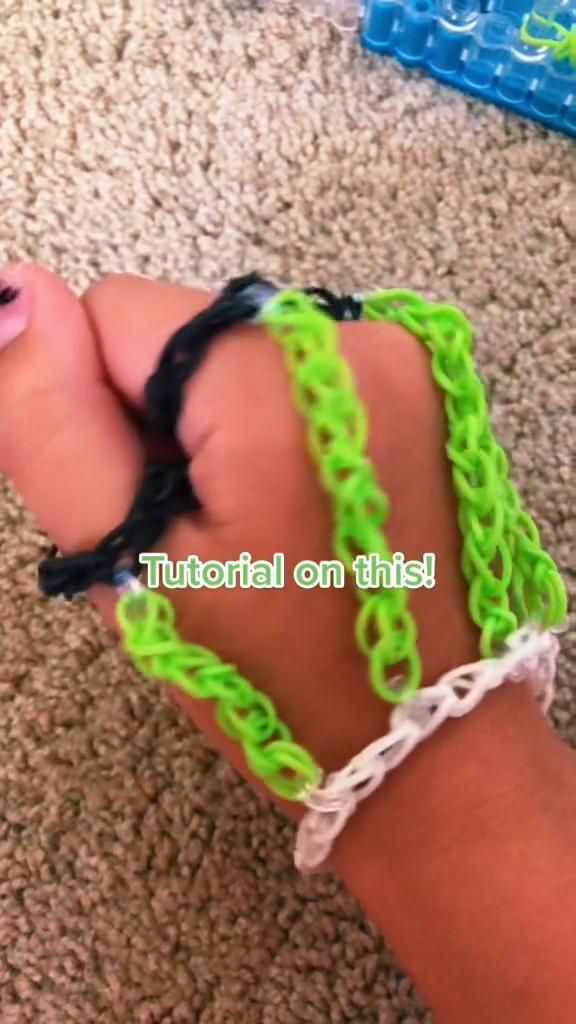 a child's hand with green and black bracelets on top of carpeted floor