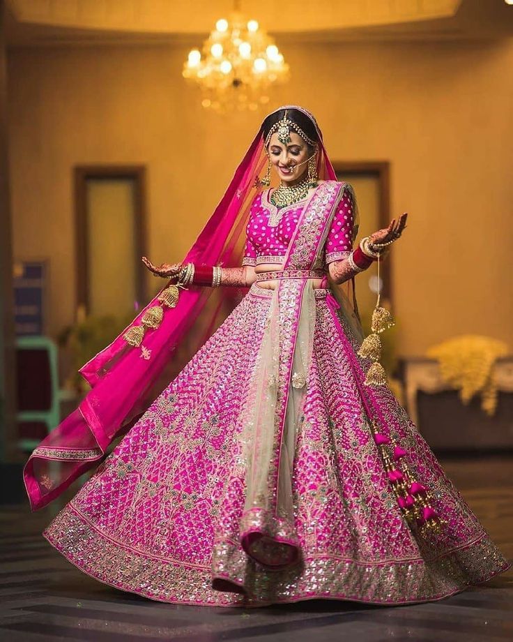 a woman in a pink and gold lehenga