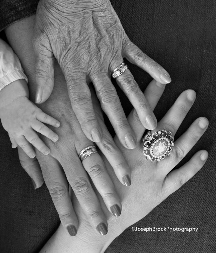 black and white photograph of an extended family holding their hands with rings on each hand