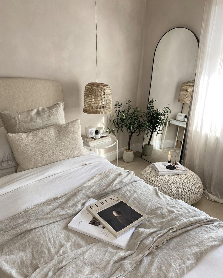 a bed with white linens and pillows in a bedroom next to a mirror on the wall