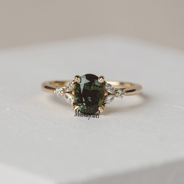 a green and white diamond ring sitting on top of a white box with diamonds around it