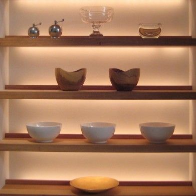 shelves with bowls and vases on them in a room