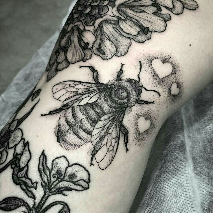 a black and white photo of a bee with flowers on it's arm,