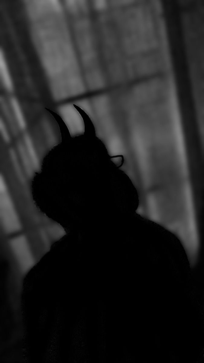 the shadow of a person with horns on their head is shown in black and white